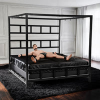 Gagged model cuffed spread-eagle to the D-rings of the King Size Bondage Bed on black sheets, Fort Troff
