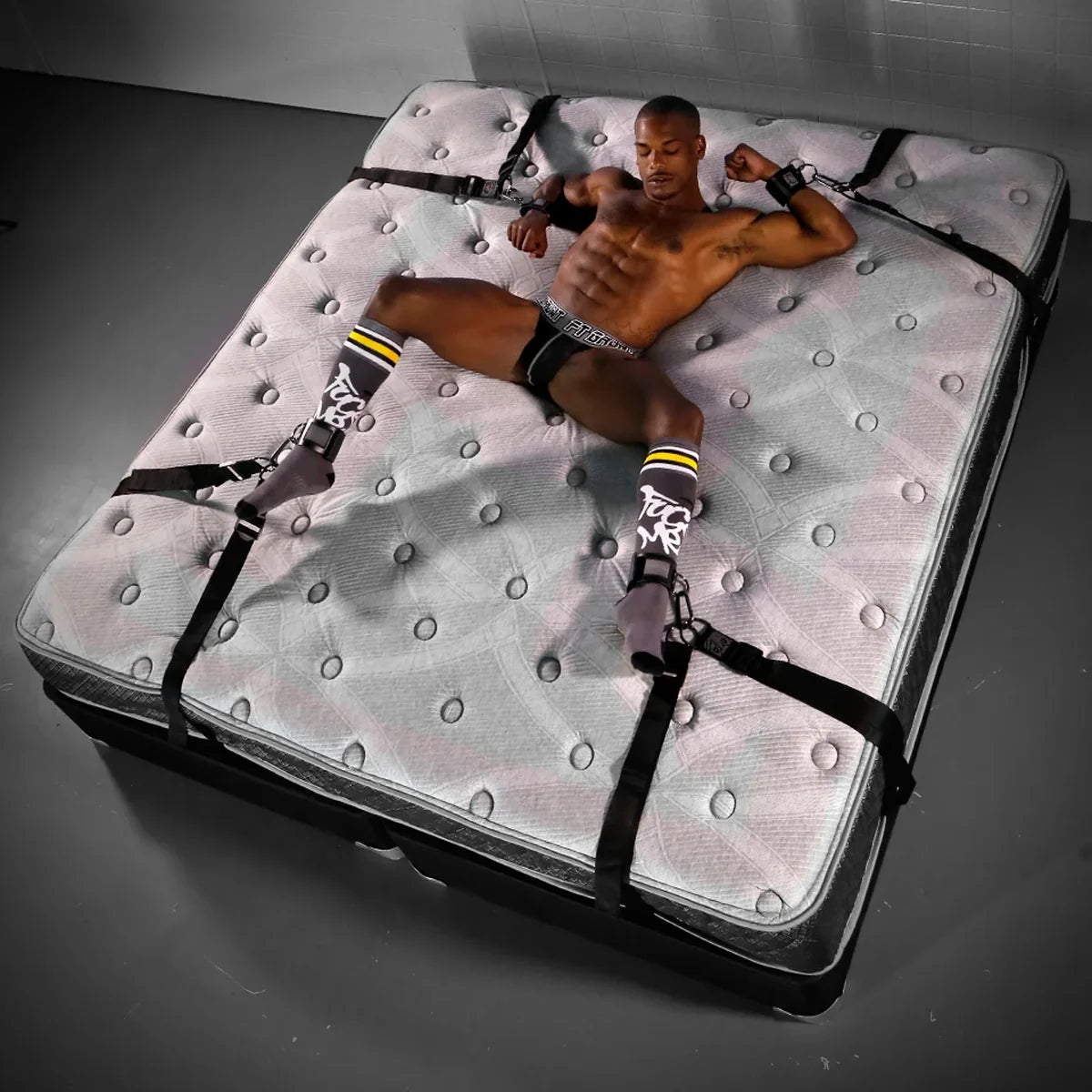 Bed Bondage under-bed restraint system laid out on a bare mattress with a model strapped spread-eagle, Fort Troff