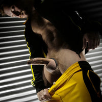 Clamp-It cock ring on a male model in a yellow and black track jacket, hard and strapped, Fort Troff