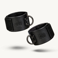Leather Ankle Cuffs pair on white, black leather with Velcro closures and gunmetal D-rings, Fort Troff