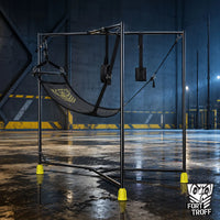 Hammock Hangar Mesh Sex Sling tri-leg steel frame with black mesh sling, stirrups and yellow boot grip feet in an empty warehouse, Fort Troff