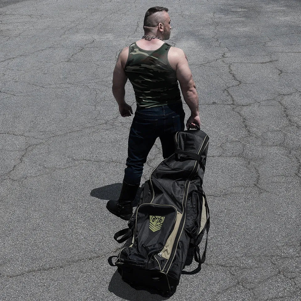 Rolling Sling Travel Bag wheeled across a parking lot by a model in a camo tank, Fort Troff