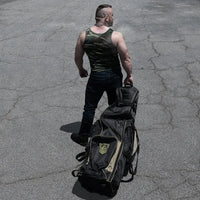 Rolling Sling Travel Bag wheeled across a parking lot by a model in a camo tank, Fort Troff